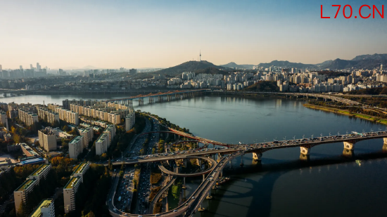 韩国首尔市中心天际线航拍图，高速公路上车流穿梭，大桥横跨汉江。